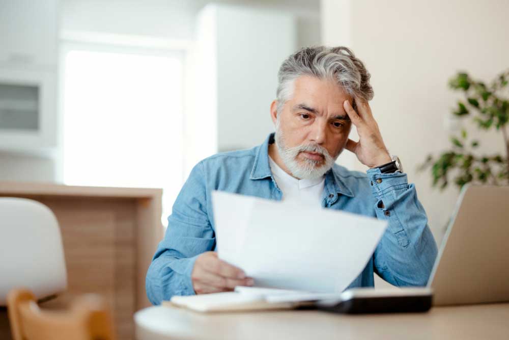 Man looks at documents, appearing concerned while reviewing FNA biopsy costs