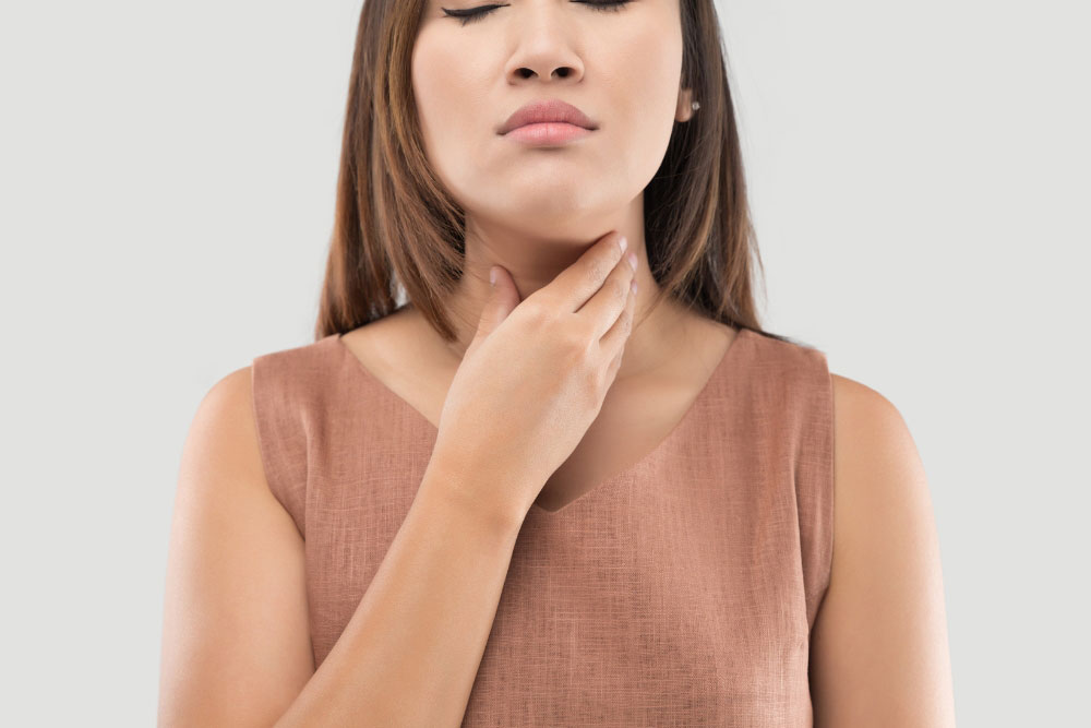 Woman touching her neck, showing possible thyroid cancer symptoms such as swelling or discomfort.