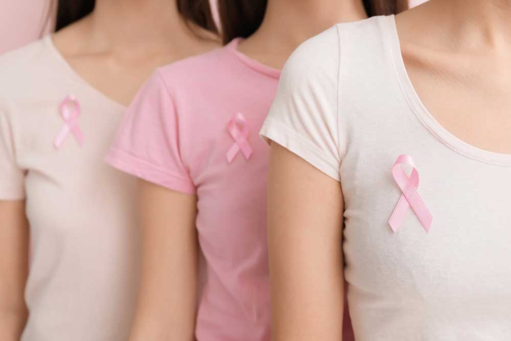 Three women in pink and white shirts stand in a row, each with a pink ribbon pinned to their chest, symbolizing breast cancer awareness and raising support for those experiencing thyroid cancer symptoms. | Cancer Biopsy & FNA Doctor in Los Angeles – Dr. Celina Nadelman Three women in pink and white shirts stand in a row, each with a pink ribbon pinned to their chest, symbolizing breast cancer awareness and raising support for those experiencing thyroid cancer symptoms. | Cancer Biopsy & FNA Doctor in Los Angeles - Dr. Celina Nadelman